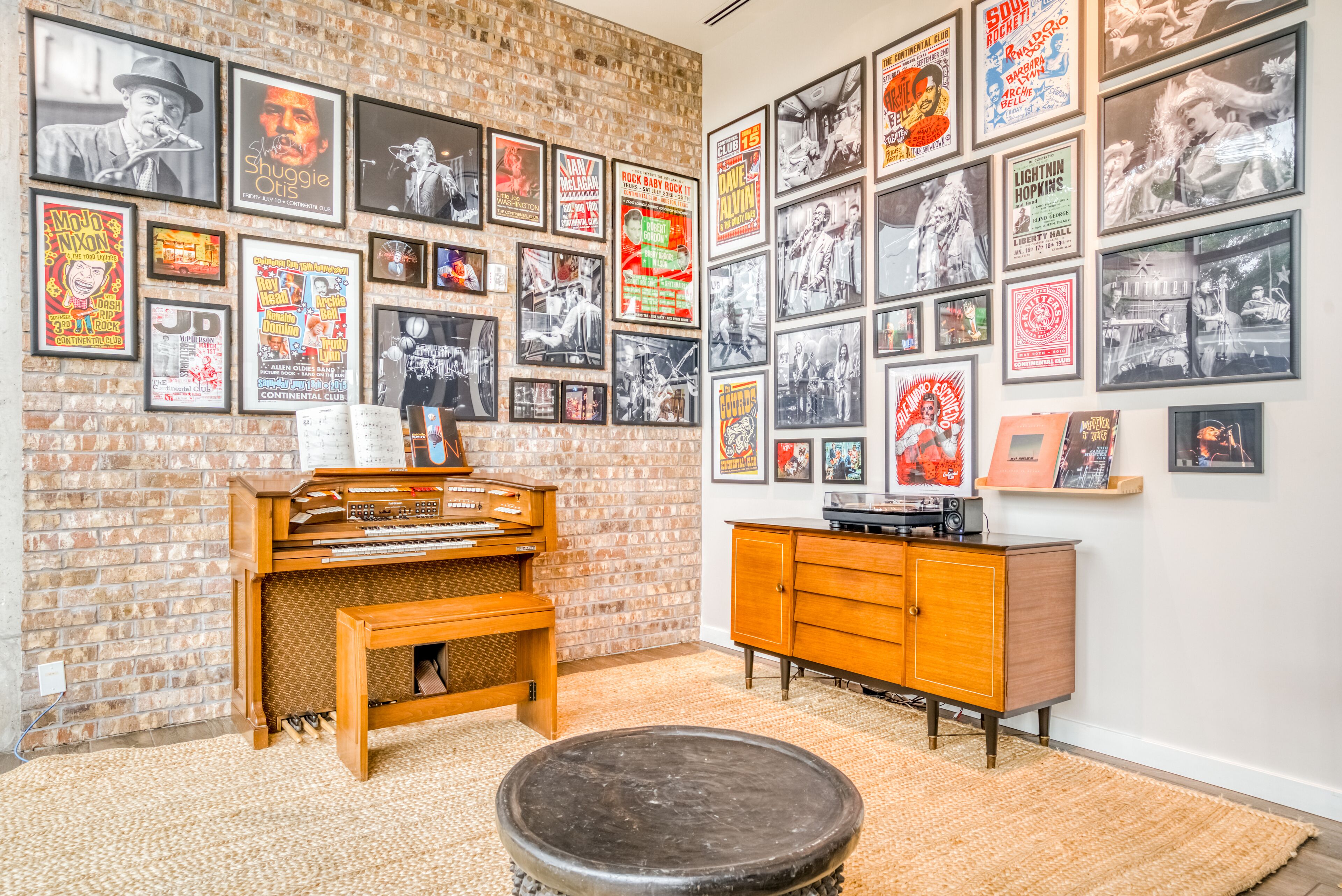 A room with a brick wall, a wooden cabinet, and a jukebox.