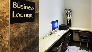 A business lounge with a marble wall, a computer, a printer, and a vase with flowers. - Gwangmyeong W Hotel (Gwangmyeong)