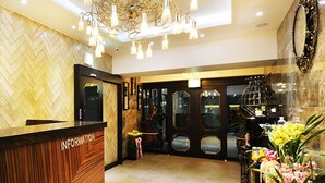A hotel reception area with a herringbone patterned wall, a reception desk labeled "INFORMATION," and a chandelier. - Gwangmyeong W Hotel (Gwangmyeong)