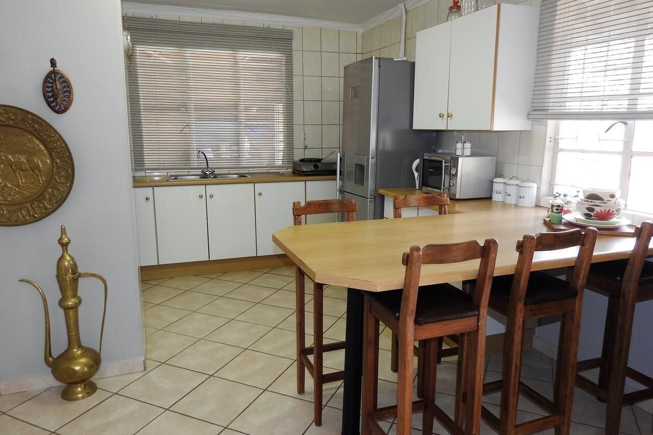 A kitchen with a wooden table and chairs, a refrigerator, a microwave, and a sink.