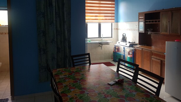 Une petite cuisine équipée d’une table à manger, de chaises, d’un réfrigérateur et d’une fenêtre avec des stores.