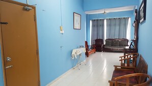 Ein Zimmer mit blauer Wand, einer Holztür, einem Sofa, einem Tisch und einem Stuhl.