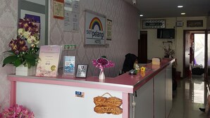 Ein Hotel-Empfangsbereich mit Empfangstresen, Deckenventilator und Wanduhr.