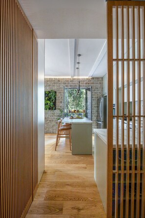 A modern kitchen with a central island, wooden flooring, and a view of the outdoors.