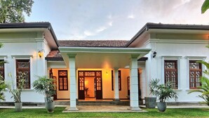 A two-story house with a covered entrance, large windows, and a well-maintained lawn. - Ali Gedara Bungalow (Galle)