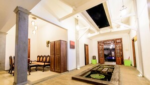 A spacious lobby with a fountain, wooden furniture, and a high ceiling with exposed beams. - Ali Gedara Bungalow (Galle)