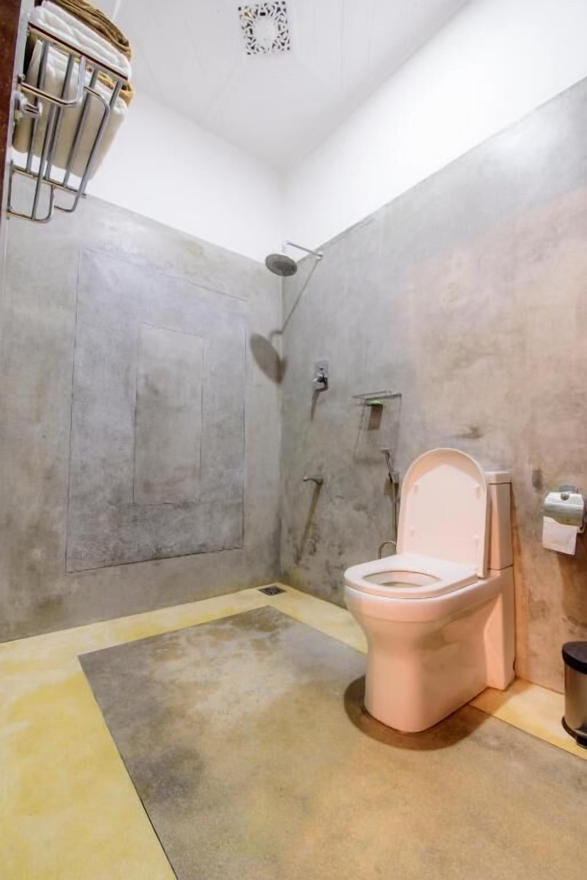 Un baño con inodoro, ducha y barra para toallas.