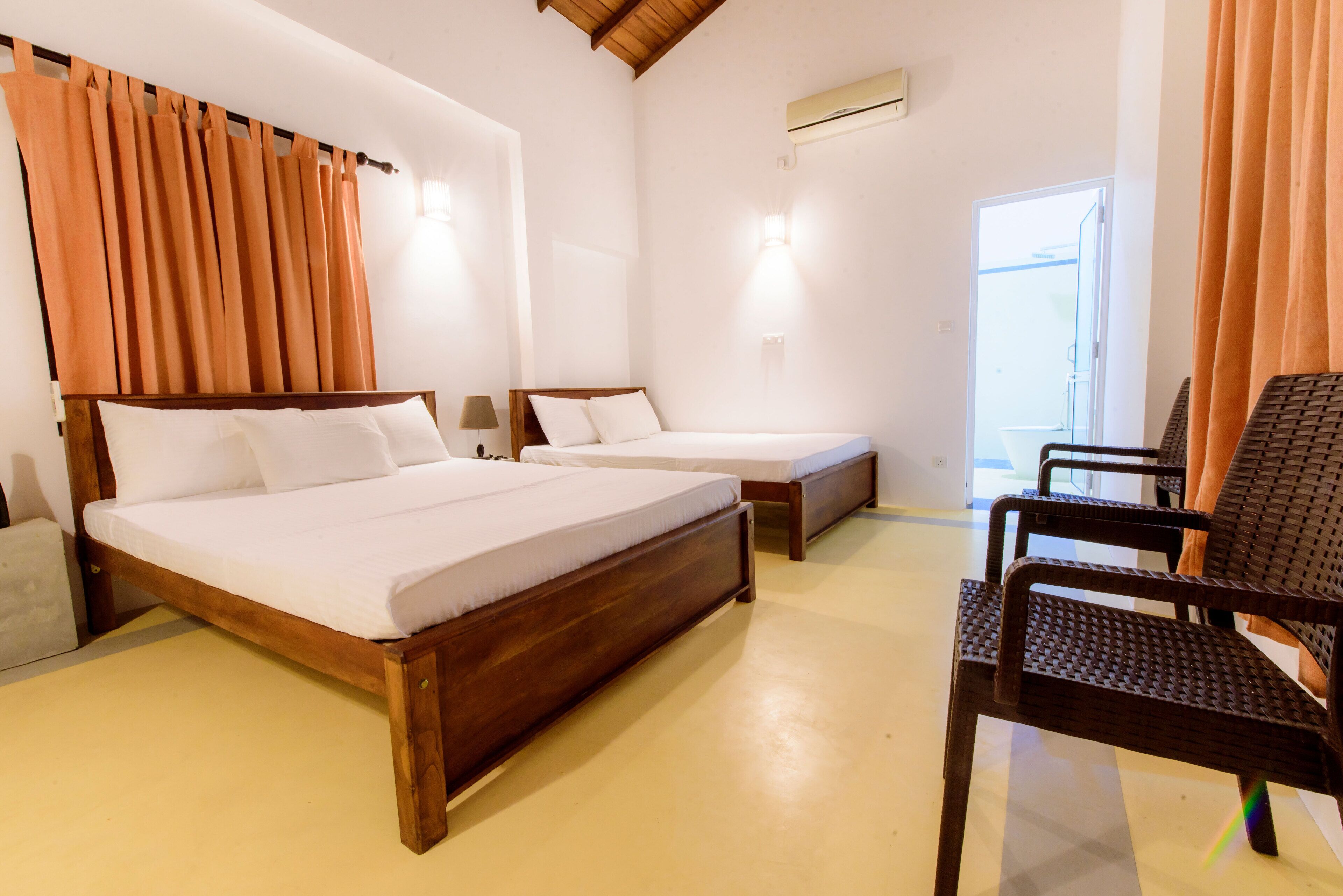 A room with two wooden beds, a chair, and a small table.