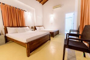 A room with two wooden beds, a chair, and a small table. - Ali Gedara Bungalow (Galle)