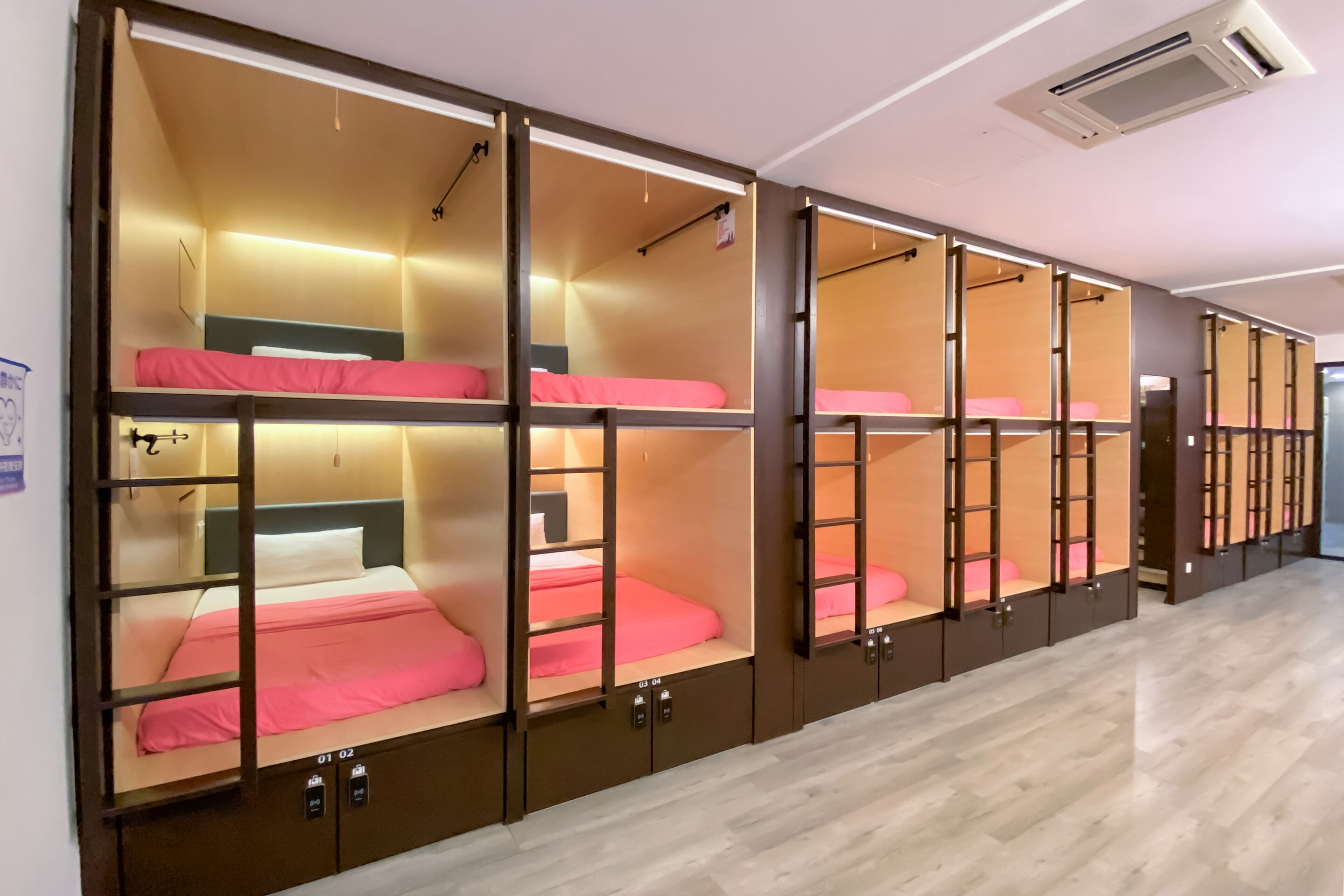 A row of bunk beds with individual lockers, each with a small shelf and a hanging light.