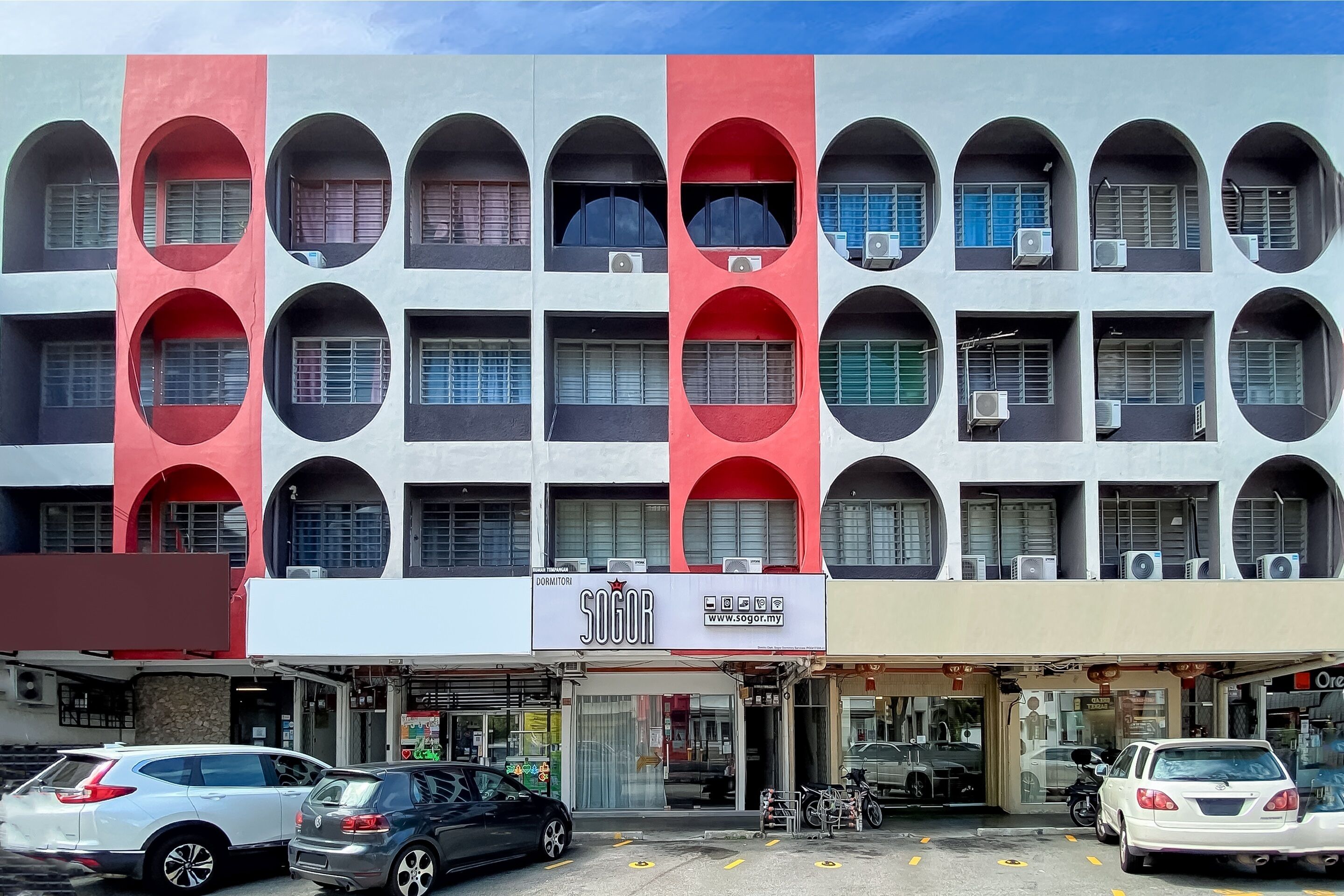 A multi-story building with a distinctive facade featuring large circular windows and a red and white color scheme.