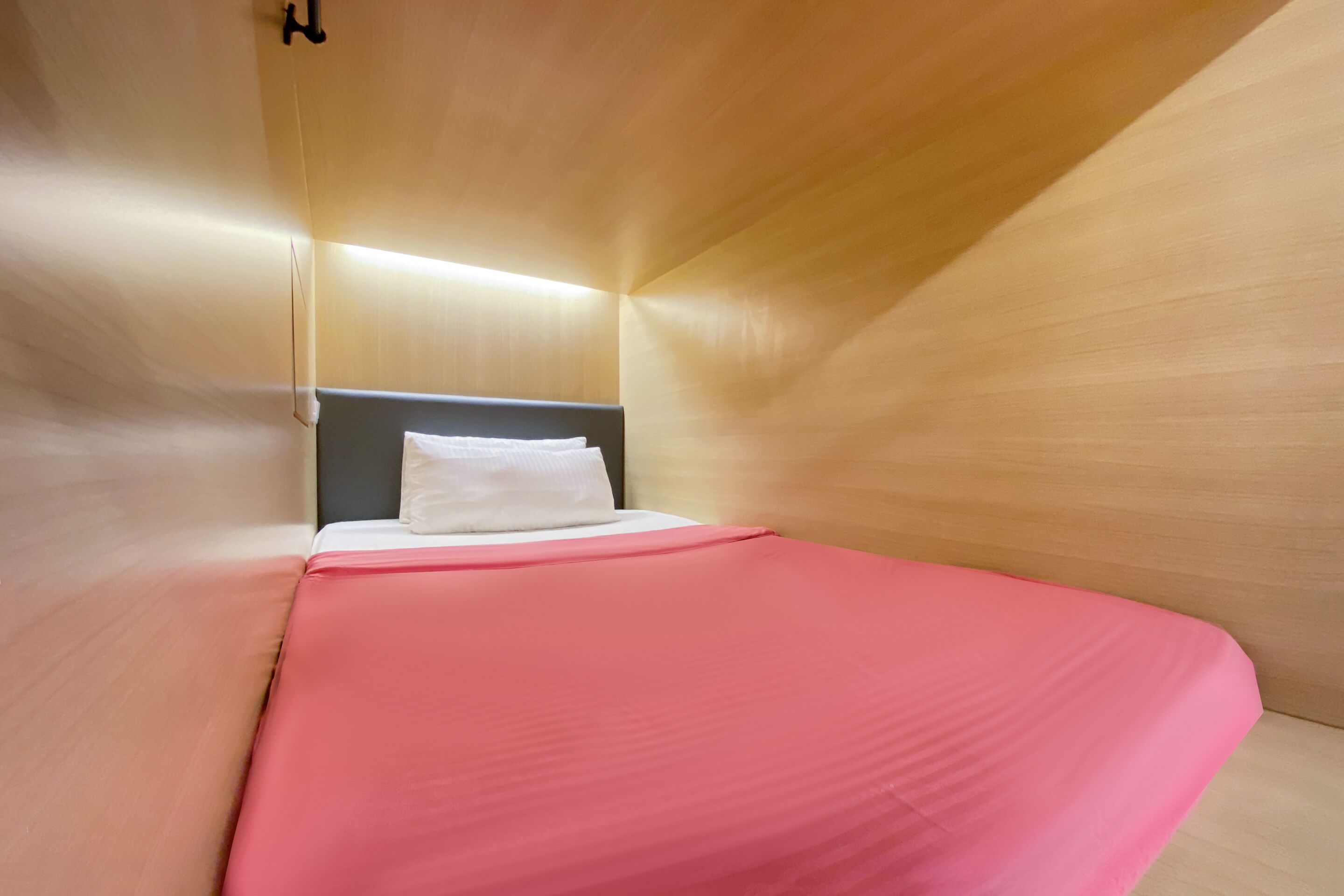 Ein modernes Zimmer mit einem Bett, Holzwänden und einem weißen Kopfkissen.