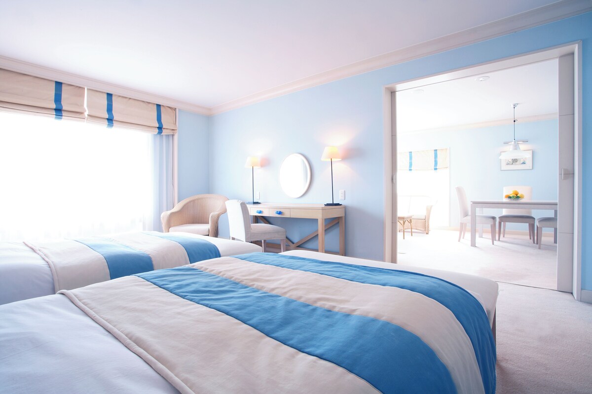 Een hotelkamer met twee bedden, een bureau en een eethoek.