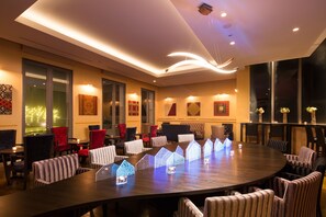 Une salle de conférence équipée d’une table ronde, de plusieurs chaises et d’un éclairage décoratif.