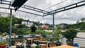 An outdoor terrace with a wooden table and chairs, surrounded by potted plants and decorative wooden elements. - Tomorrow Homestay Da Lat (Xuan Huong - Da Lat)