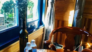 A wooden table with a glass top, a bottle of Aquafina water, two water bottles, a glass, and a pine cone. - Tomorrow Homestay Da Lat (Xuan Huong - Da Lat)