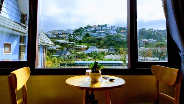 A room with a window overlooking a hillside of houses. - Tomorrow Homestay Da Lat (Xuan Huong - Da Lat)