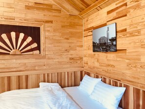 A wooden-paneled room with a bed, a fan, and a framed picture on the wall. - Tomorrow Homestay Da Lat (Xuan Huong - Da Lat)