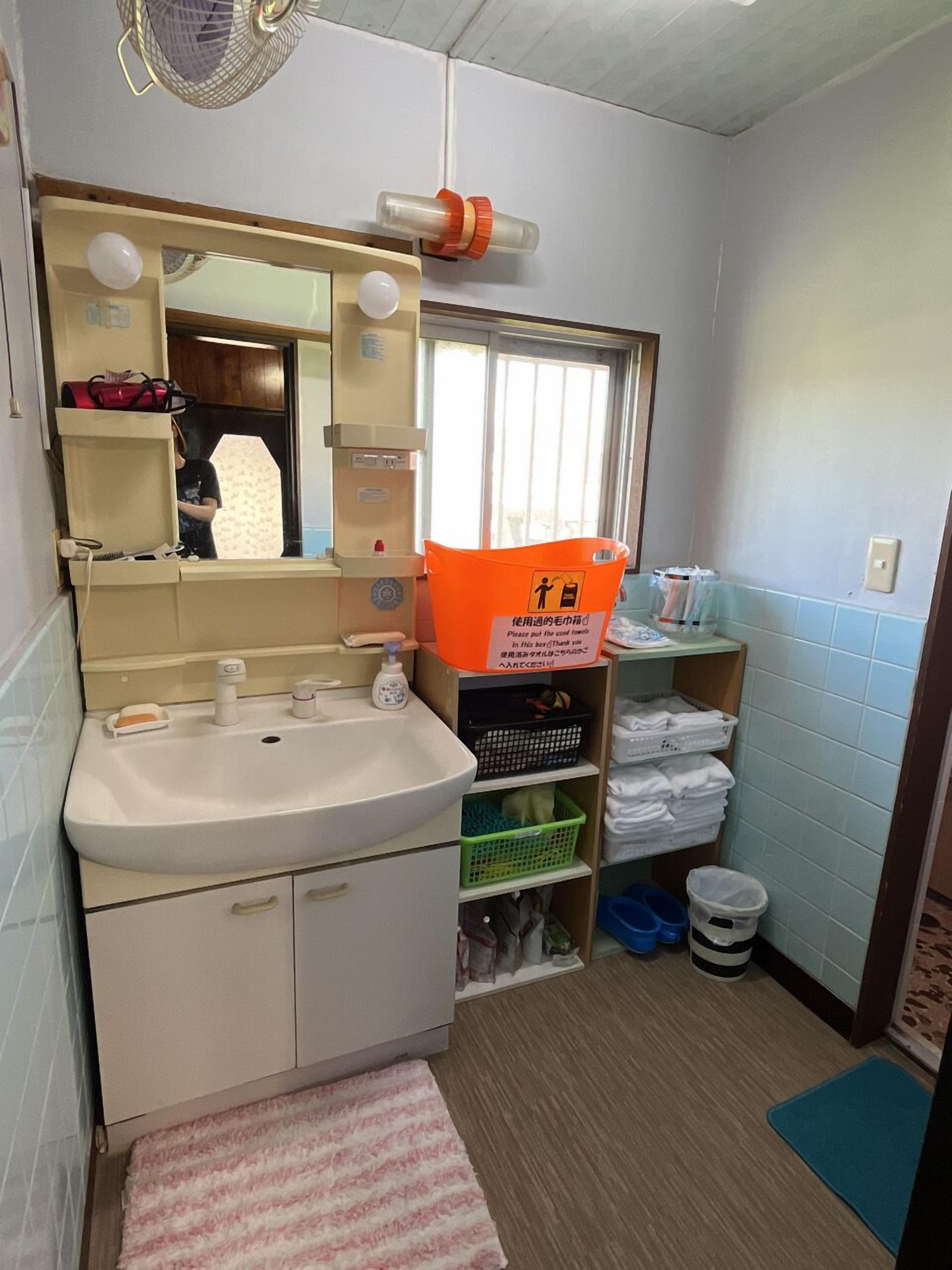 Casa de banho compacta com lavatório, espelho e estantes para arrumação.