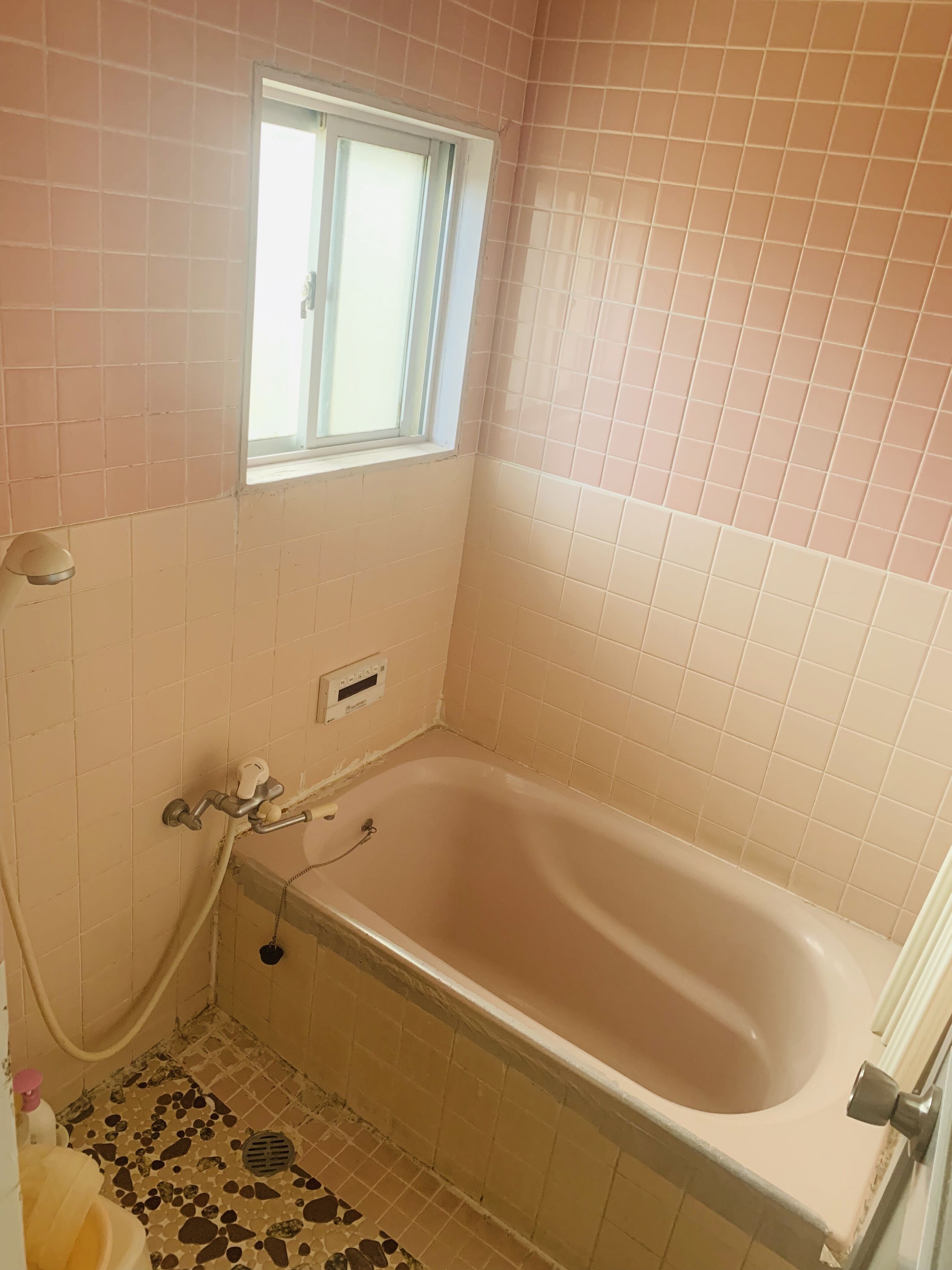 A bathroom with a bathtub, a window, and a tiled floor.