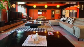 A modern living room with a sofa, coffee table, and TV. There are checkered rugs on the floor and a plant in the corner. - Airport Osaka (Kaizuka)