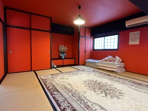 A tatami mat room with a large tatami mat, a low table with a vase, and a window with a calendar. - Airport Osaka (Kaizuka)