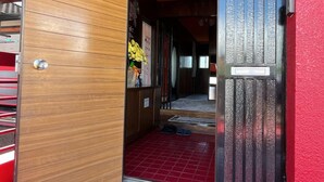 A red-tiled entrance with a wooden door and a metal gate. - Airport Osaka (Kaizuka)
