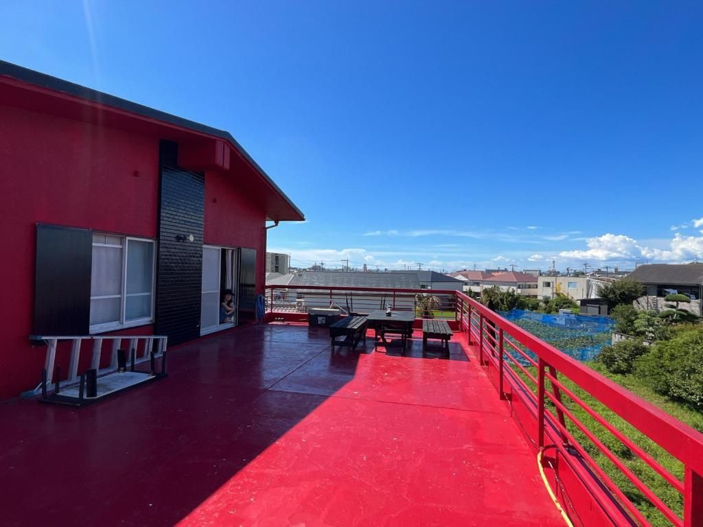 Un edificio rojo con techo rojo, un balcón rojo con barandilla y vistas del entorno.