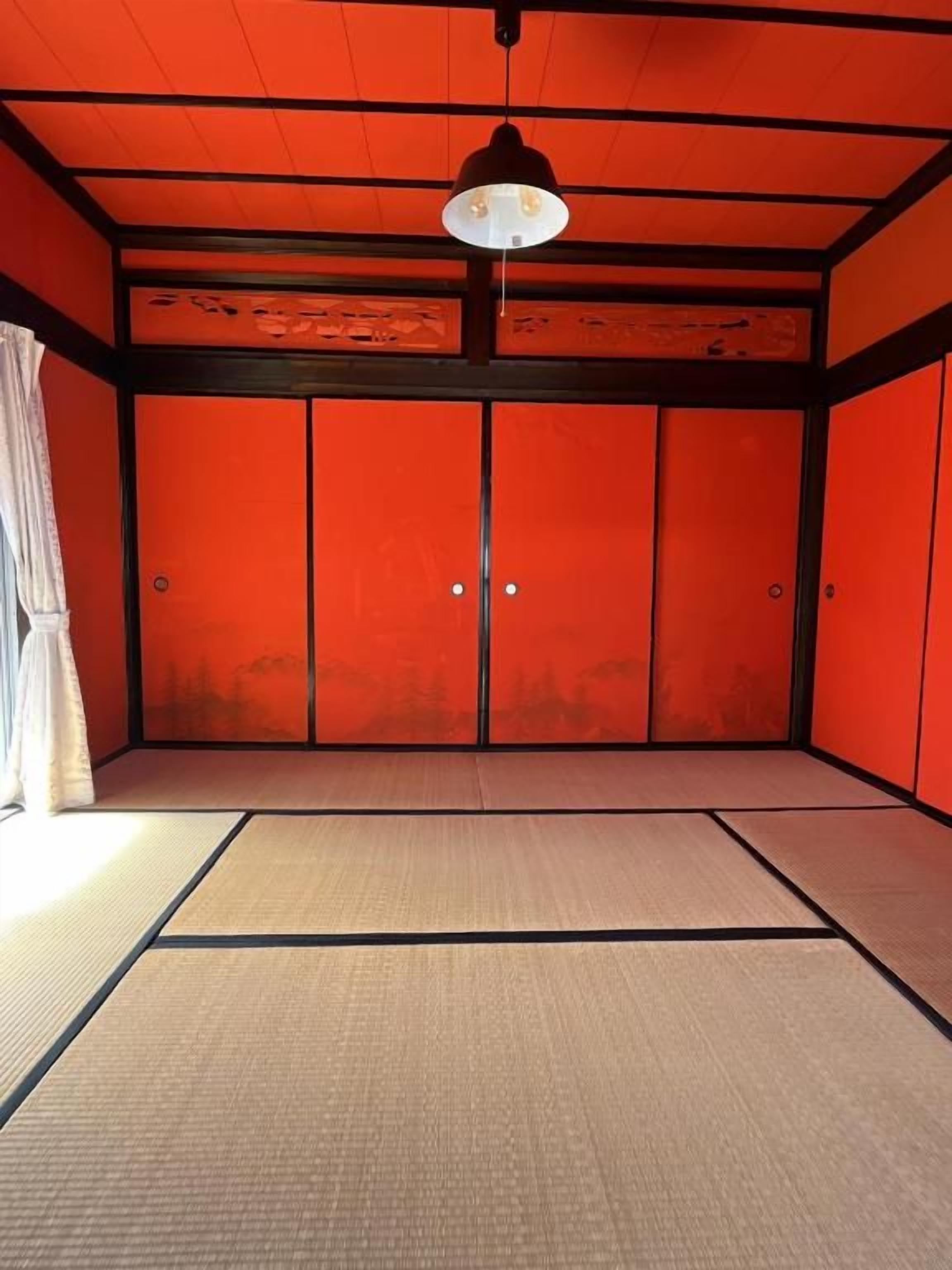 Ein Zimmer mit Tatami-Böden, einer Shoji-Schiebetür und einer Pendelleuchte.