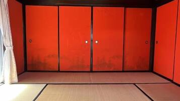Ein Zimmer mit Tatami-Böden, einer Shoji-Schiebetür und einer Pendelleuchte.