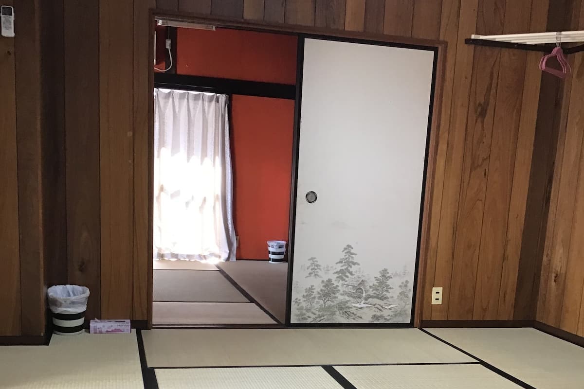 Een kamer met tatami matten en een schuifdeur die leidt naar een andere kamer.