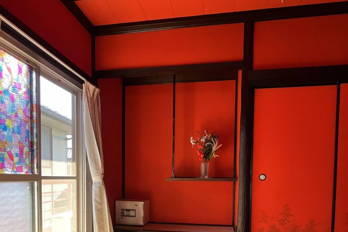 Een kamer met tatami matten, een schuifdeur, een tafeltje met een radio en een vaas met bloemen.