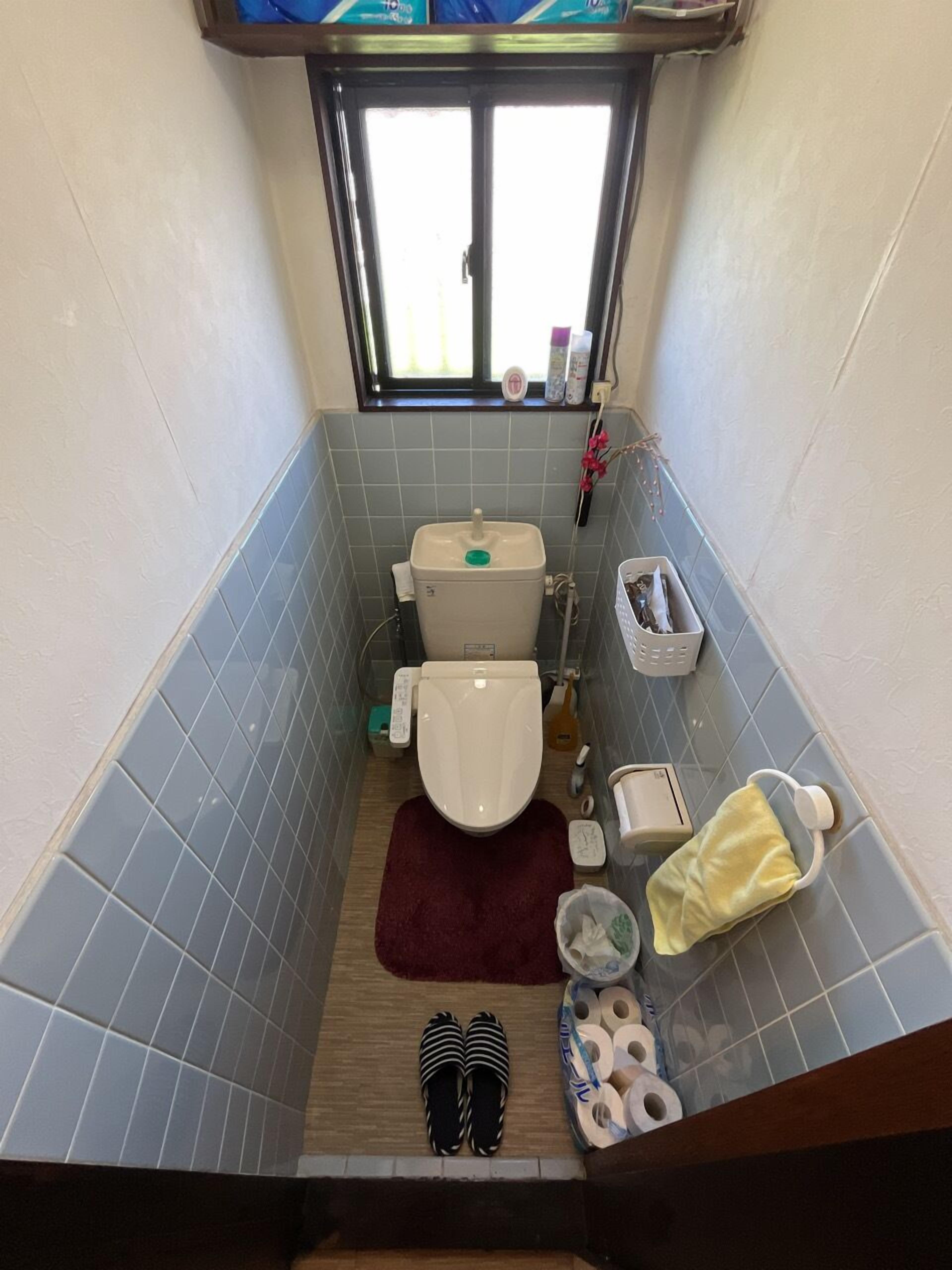A small bathroom with a toilet, a sink, and a window.