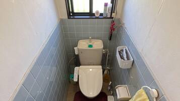 A small bathroom with a toilet, a sink, and a window.