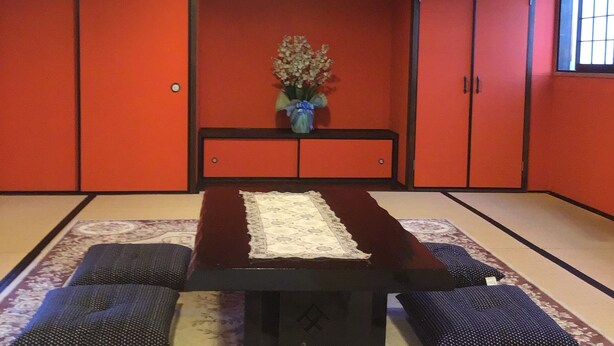 A traditional Japanese room with tatami flooring, a low table, cushions, and a hanging light fixture. - Airport Osaka (Kaizuka)