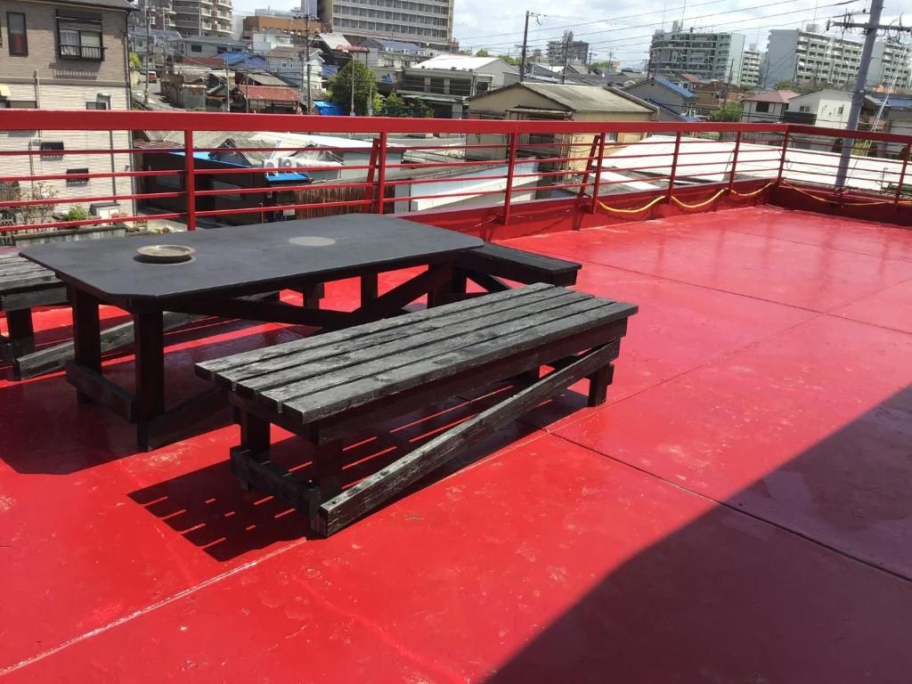 Een rood terras met picknicktafels en een balustrade.
