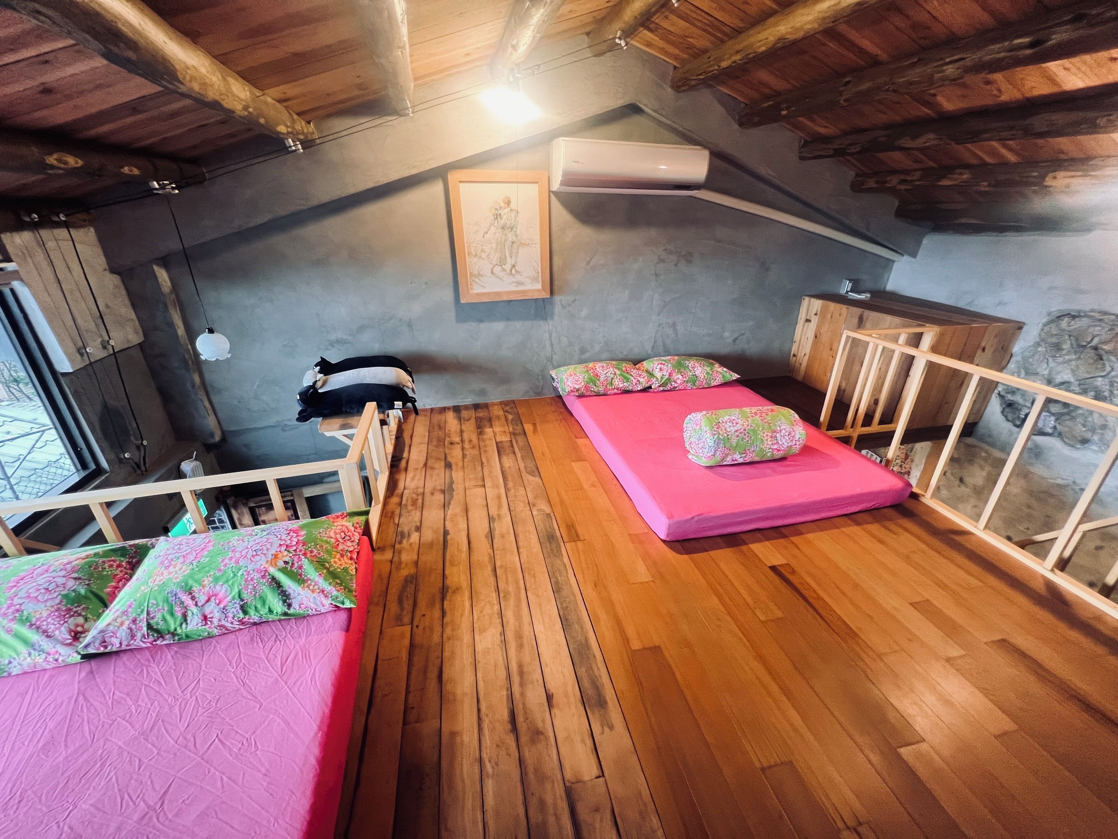 A loft bedroom with wooden floors, a sloped ceiling, and a bed with floral bedding.