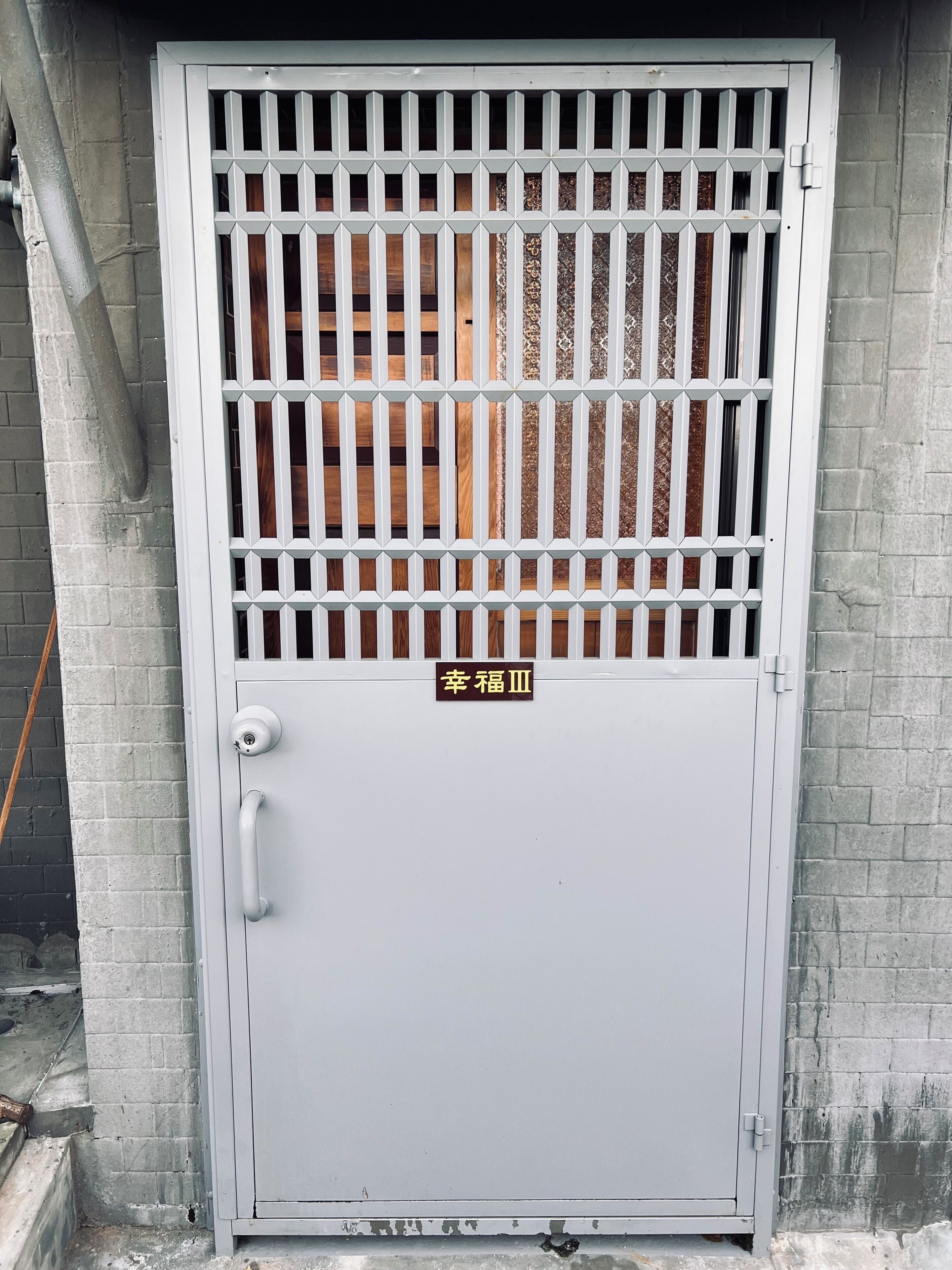 A metal security gate with a keypad and a sign above it.