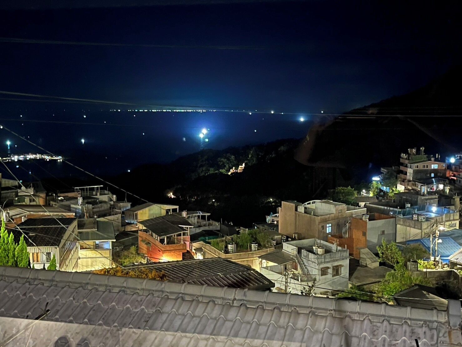 A nighttime view of a residential area with buildings and a bridge in the distance.
