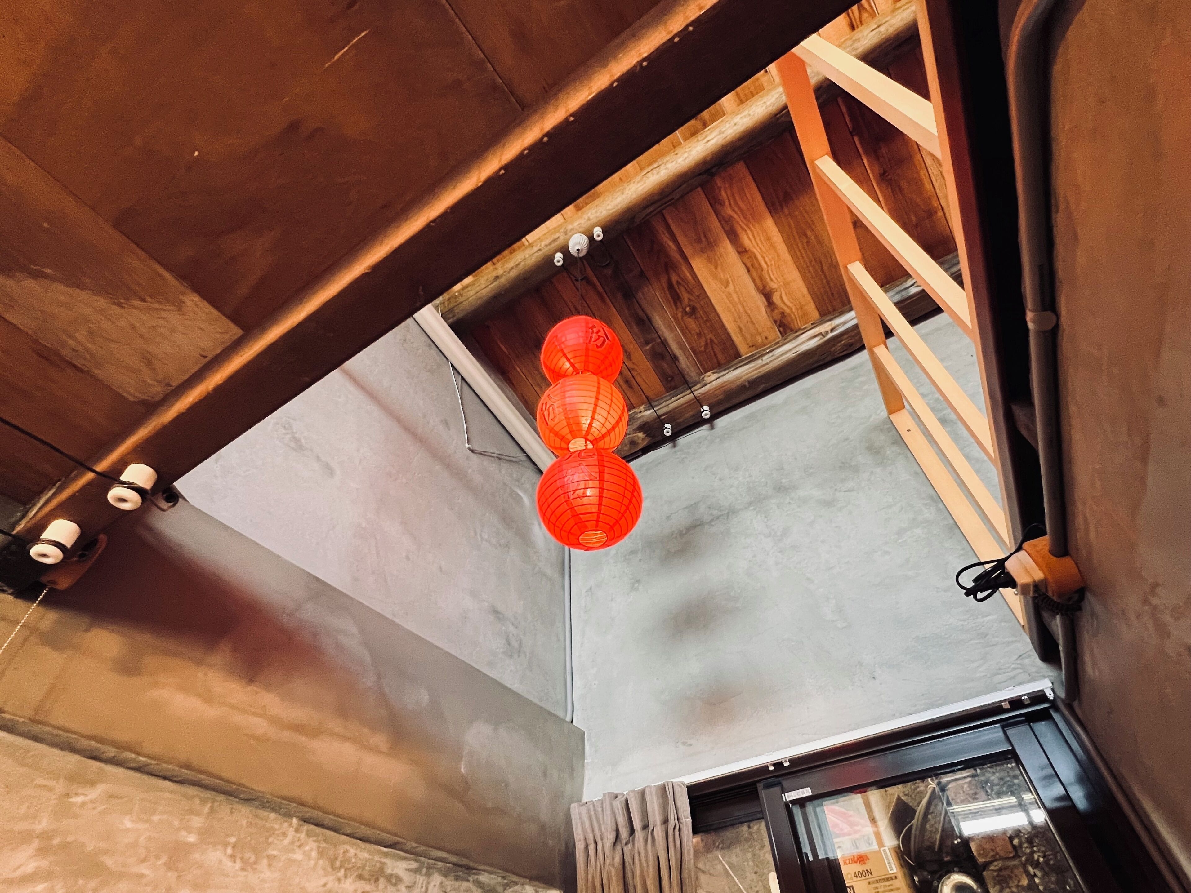 A room with a concrete floor, wooden beams, and a staircase.