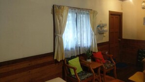 A room with wooden walls and ceiling, a wooden bench, a small table with a plant, and a door. - Hua Shan Hor Yuan Homestay (Meishan)