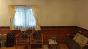 A living room with wooden flooring, a sofa, two armchairs, a small table with a vase, and a window with curtains. - Hua Shan Hor Yuan Homestay (Meishan)