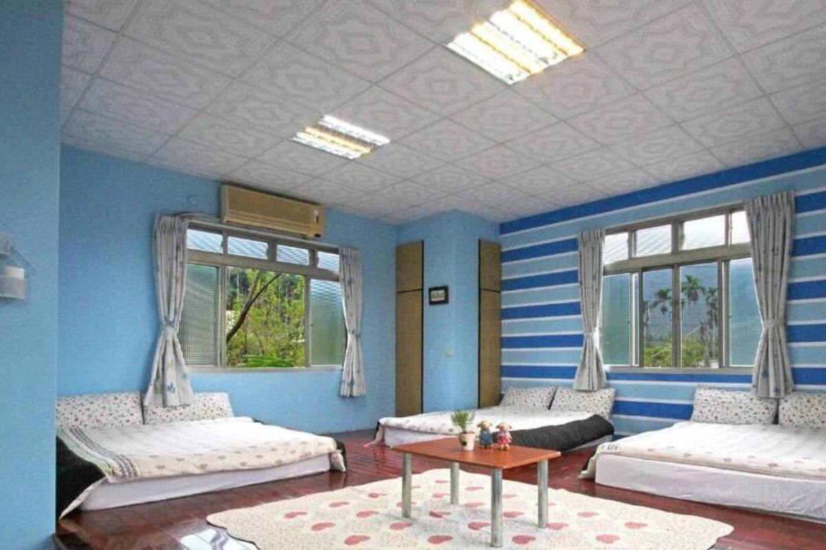 Een kamer met twee bedden, een klein tafeltje en grote ramen.