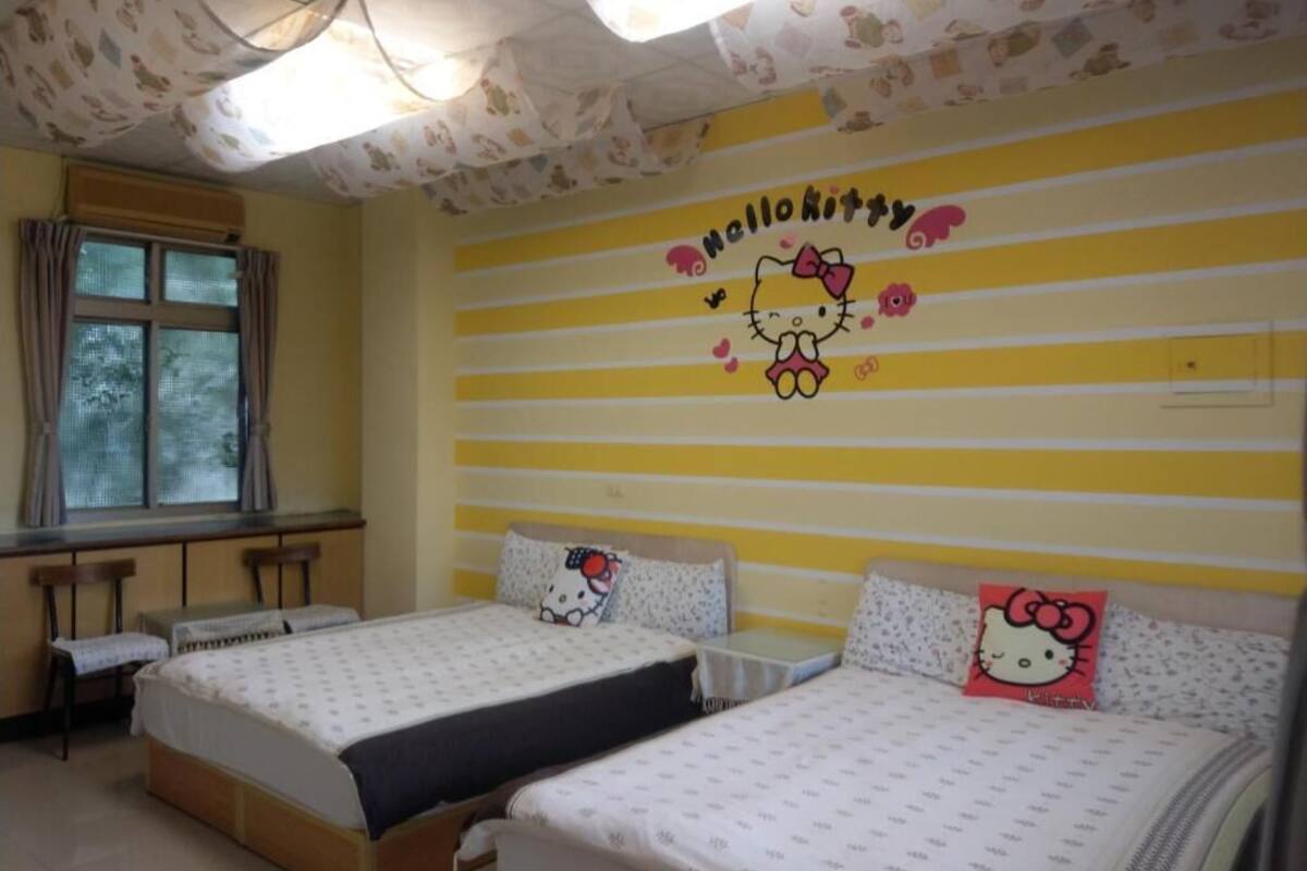 Een kamer met twee bedden, elk met beddengoed en kussens met een Hello Kitty thema.