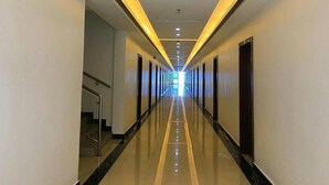 Un pasillo largo y bien iluminado con piso reflectante, que conduce a una salida luminosa al final.