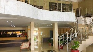 Un vestíbulo de hotel con una recepción, una escalera y un área de estar.