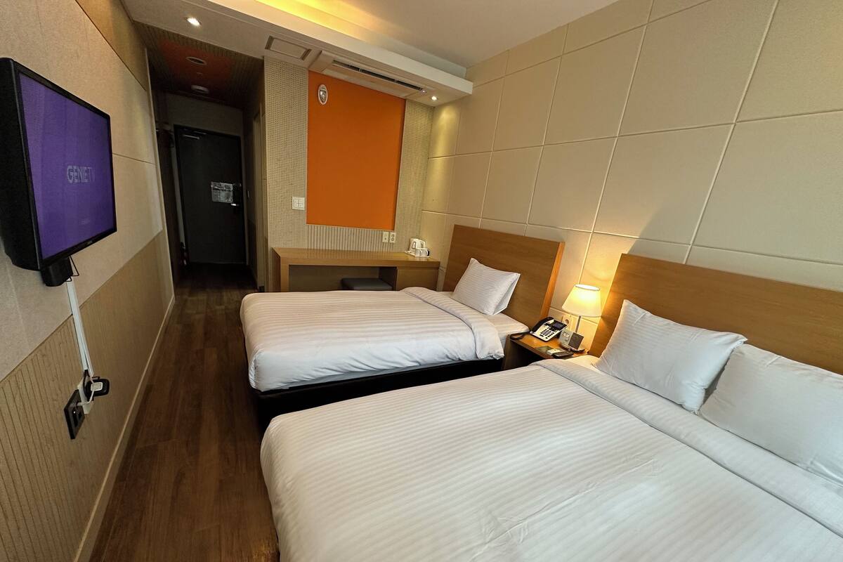 Habitación de hotel con dos camas, televisión, escritorio y teléfono.
