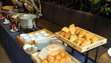 A buffet setup with various food items, including baked goods and bread, arranged on a table with a blue tablecloth.