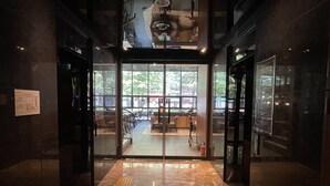 A modern interior with a glass door entrance, a tiled floor, and a ceiling with a unique design. - Hotel ICC (Daejeon)