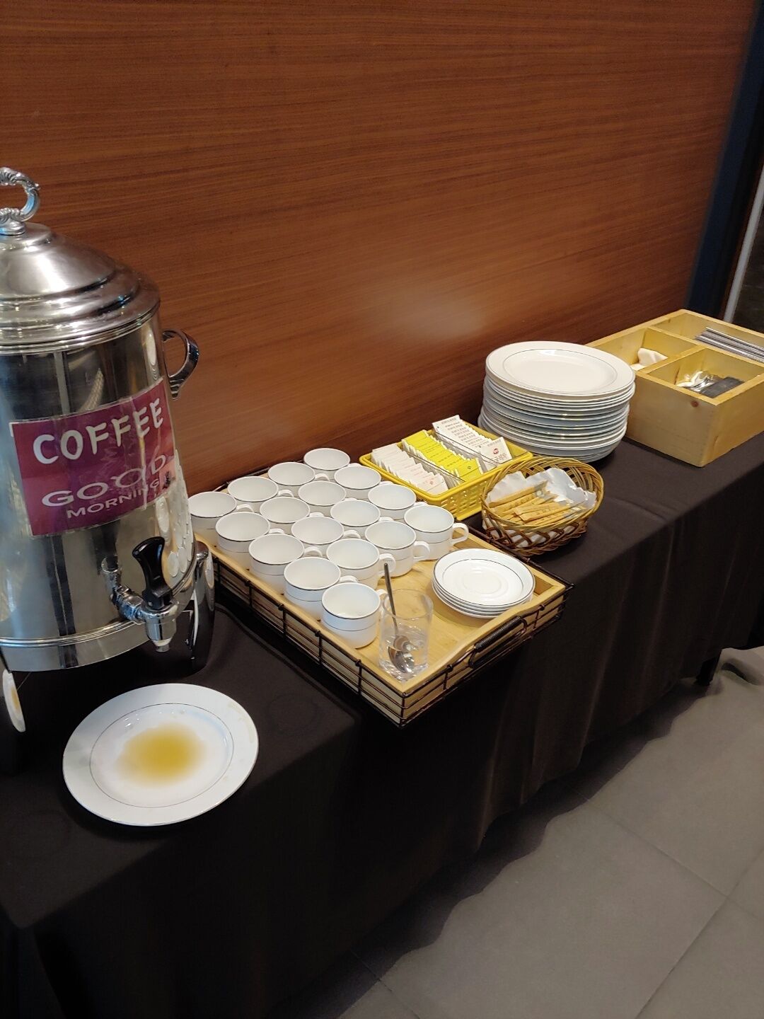 Un buffet avec un distributeur de café, des piles d’assiettes, des bols et des paniers.